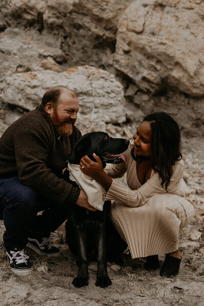 bride and groom kissing infront of red rocks with their dog