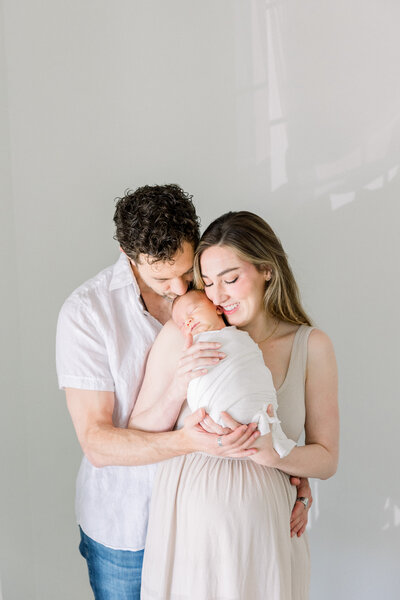 Image of new mother kissing baby's head while baby rests on her chest taken by maternity photographer sacramento Kelsey Krall