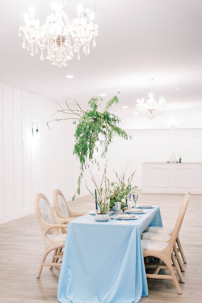 stunning blue and cream wedding  table and settings in Tampa FLorida with a bright chandelier over the table taken by  best wedding photographers in Tampa Florida