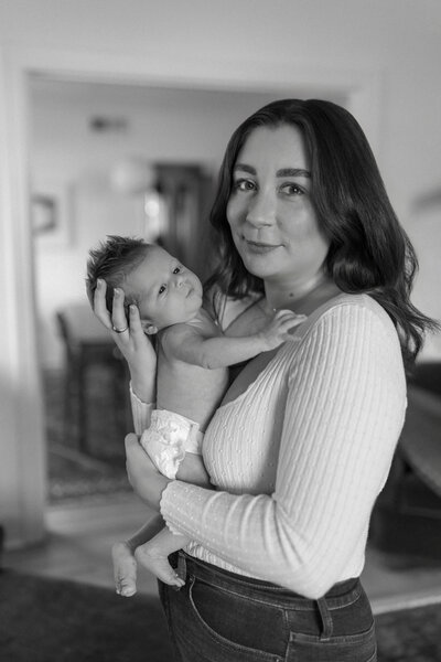 mom holding newborn pose in home newborn session in stockton california