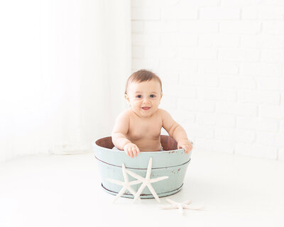 Baby boy sitting in a blue bucket