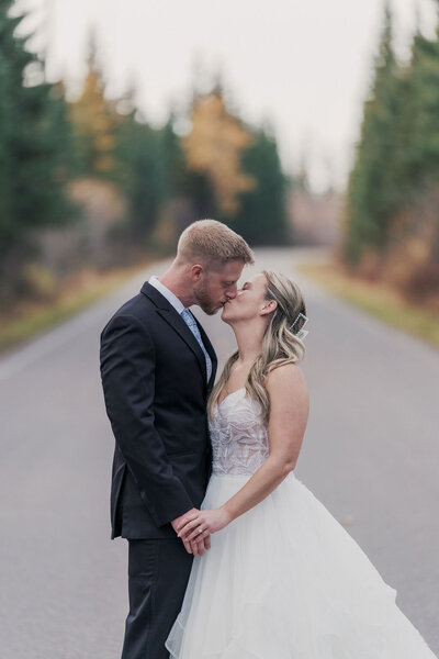 Couple dancing on a rocky cliffside with forest and river views, captured by Joseph Mayden during an outdoor adventure session in Montana.