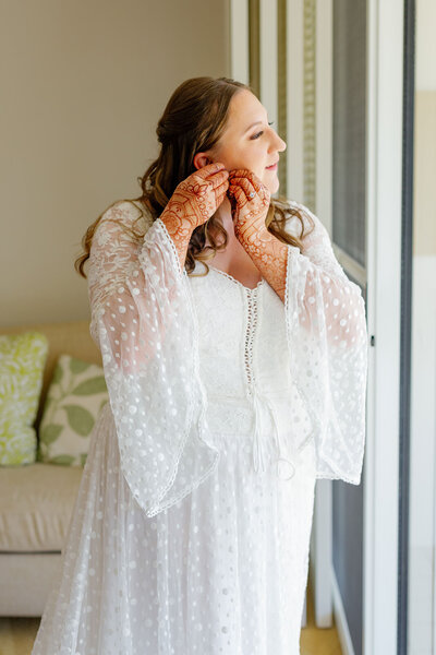 A person in a wedding dress putting on earrings 