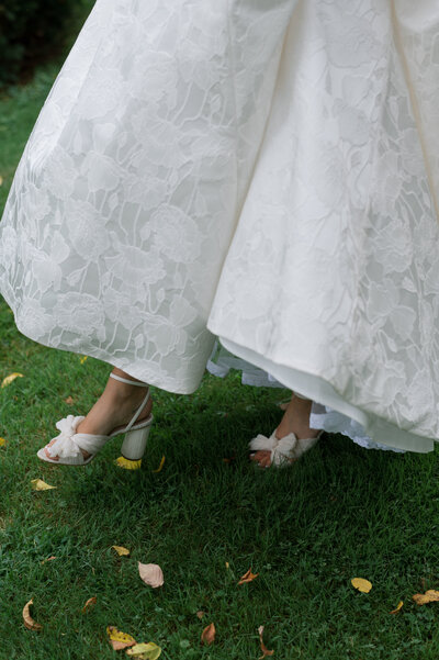 close up of bride walking in bow bridal shoes and lace gown