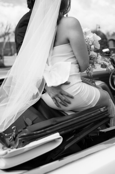 A couple sitting on the top of the seats in a convertible