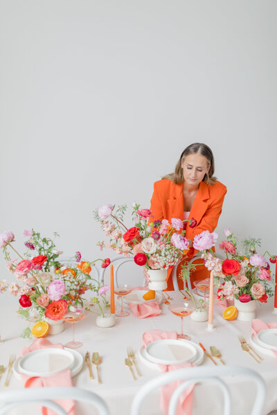 AE & F, Lancaster floral designer places colorful pink toned floral display on  a table.