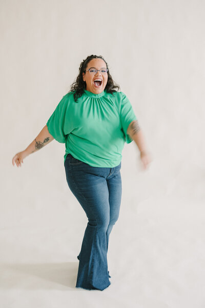 A person standing in a white room laughing and swinging their arms