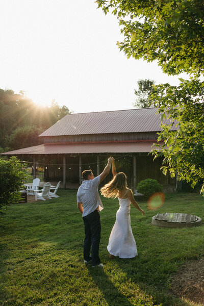Man spinning a woman in a soft light of golden hour among the hills of Asheville NC, documented by Andrea-Marie Photography