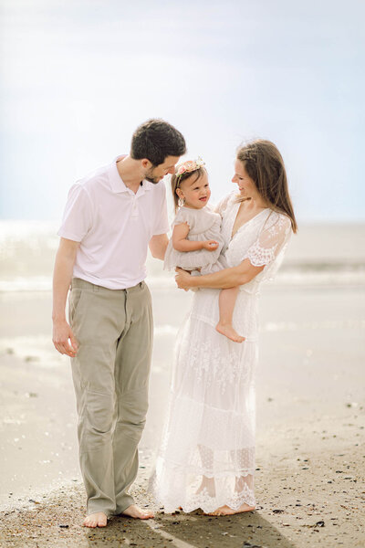 Family of 3 standing by the ocean on the Outer Banks beach