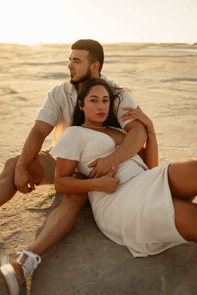 couple sitting in the sand snuggling together