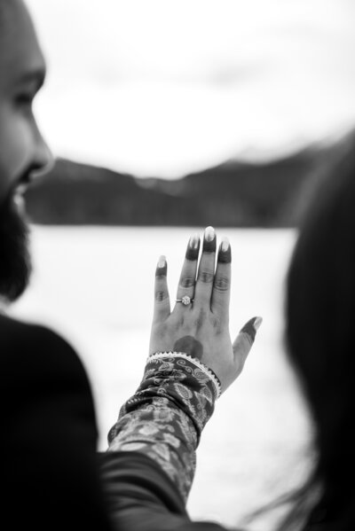 Photo of fiancee holding up her engagement ring with man looking at her lovingly