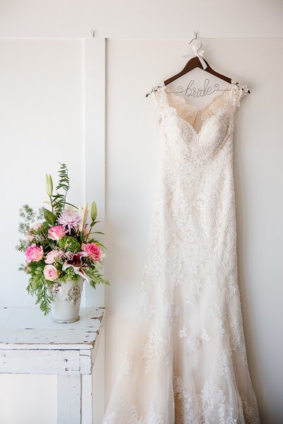 Detail photo of bride and bridesmaid holding Anemone bouquets with heavy greenery and white roses