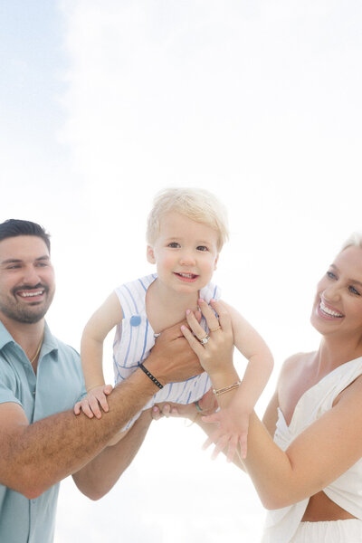 A mom and dad playing with their smiling toddler at their sunset photo session in Grand Forks. 