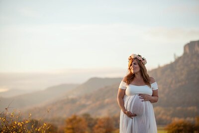 Pregnant woman in sheer white dress with Table Rock behind her