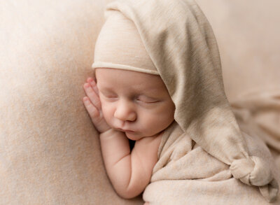 A sleeping baby on cream fabric in Utah.