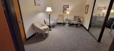 Therapist office with grey carpet and tan armchairs