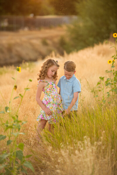 twin siblings standing in a field in boise during pictures with photographer Tiffany Hix