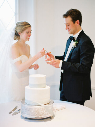 A portrait of a bride and groom cutting their wedding cake