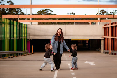 Mother and her two sons playing at a roof top carpark with vibrant colour accents