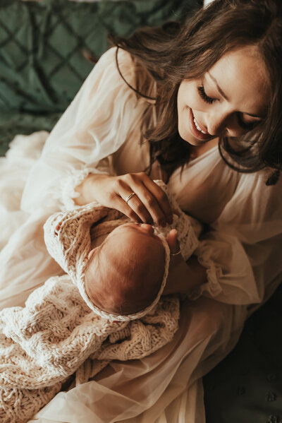 A mother holding and admiring her newborn baby.