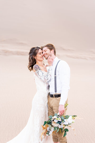 Bride bringing her hand up to the groom's face to snuggle in close while laughing together 