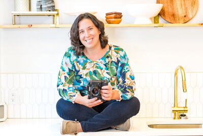 Photographer sitting on counter with camera in her hands