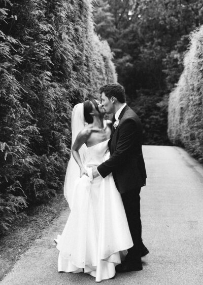 a black and white photo of a bride and groom kissing