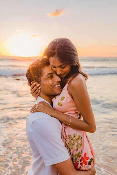 woman leaps over wave with her boyfriend in hawaii
