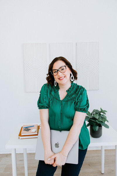 Copywriter Sara Gillis with laptop and arms in the air celebrating