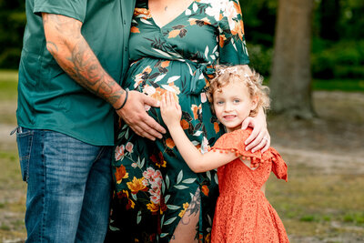 family embracing mom-to-be's pregnant belly in a park