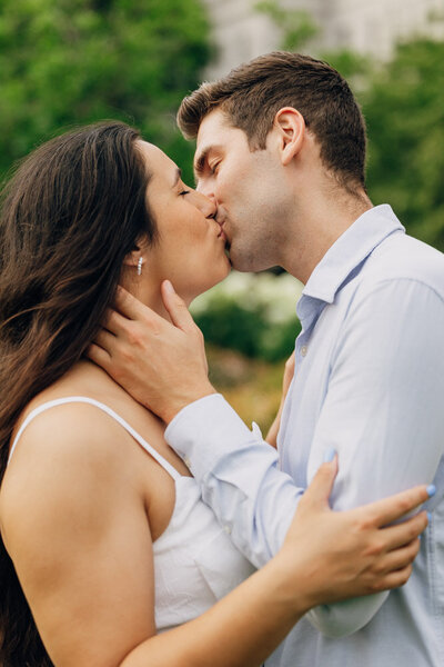 Close up of engaged couple in a tight embrace kissing.