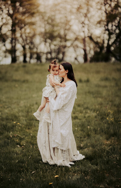 en mamma och dotter står på ett fält och pussar varandra