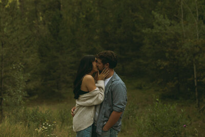 Close up of a couple sitting in a red convertible car. She has her legs crossed and hanging out of the side.