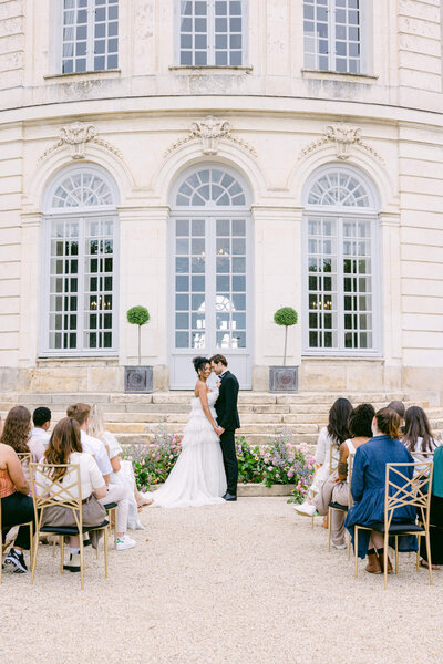 picture of a couple during their wedding ceremony  surronded by their guests with chateau du grand luce in the background.