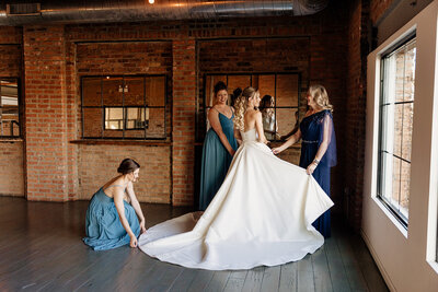 Bridesmaids help bride get ready on wedding day