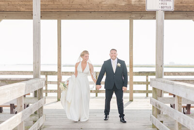 Newlyweds walk along a wooden dock holding hands for a Detroit Wedding Photographer