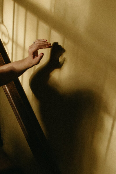 silhouette with hand visible walking down the stairs 