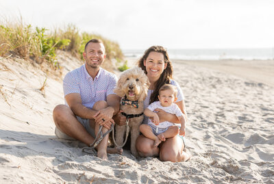 family with dog and baby sitting on beach in ocean city nj