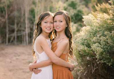 Two sisters snuggling during their gorgeous Rancho Santa Fe family photography session at the San Elijo lagoon