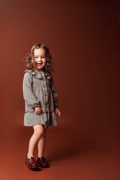 studio personality portrait of a smiling young girl twirling