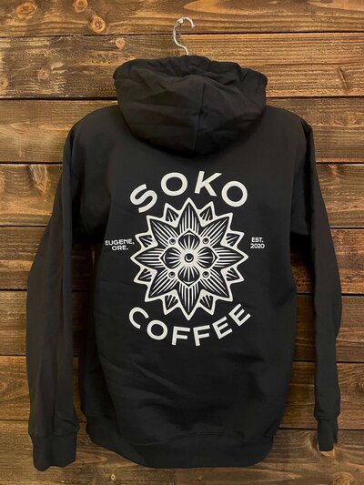 Back of Solo Coffee printed black hoodie with intricate flower design.
