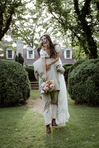 Bride standing in a lush garden holding her bouquet, surrounded by spring greenery and timeless architecture, celebrating her intimate Atlanta elopement.
