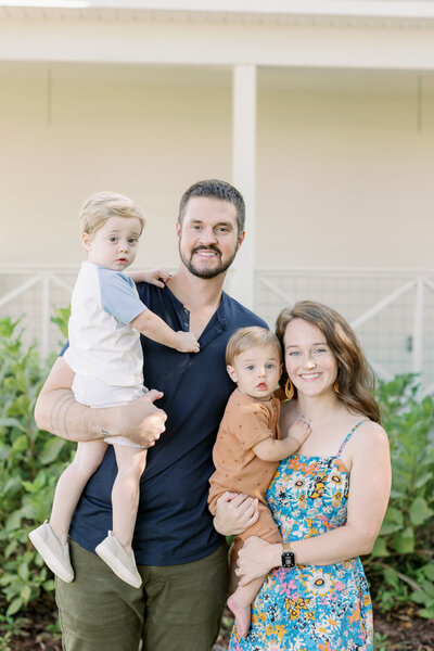 Family smiling in front of a home