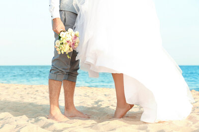 Bride and groom standing at the seashore on their feet