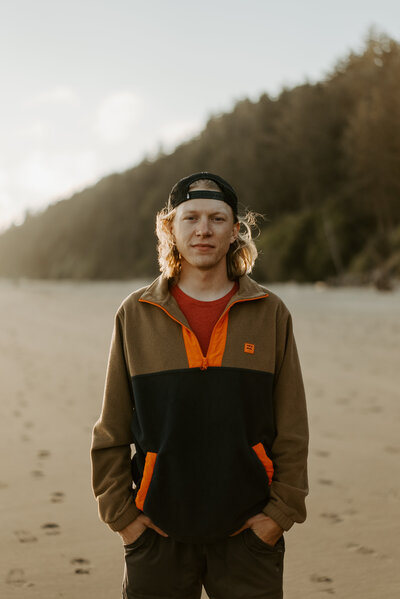 Photo of Adam standing on the beach with his hands in his pocket