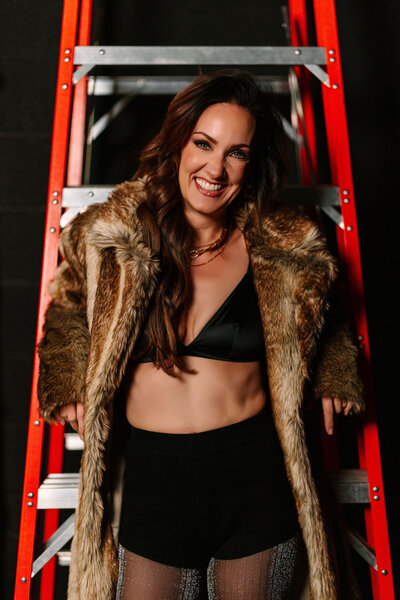 Photo of Juliet Trnka in a fur coat with a metal red ladder behind