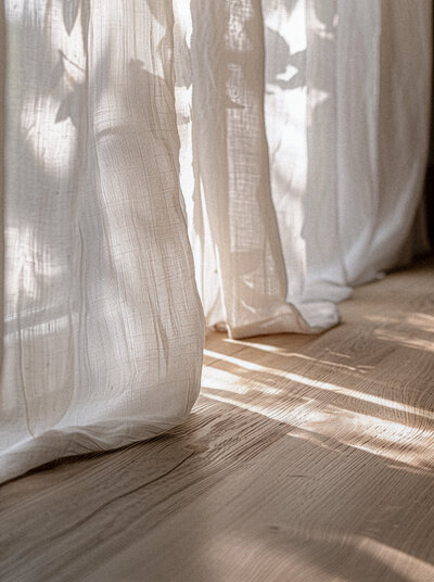 Long sheer white curtains, sunlight pouring through, wooden floorboards