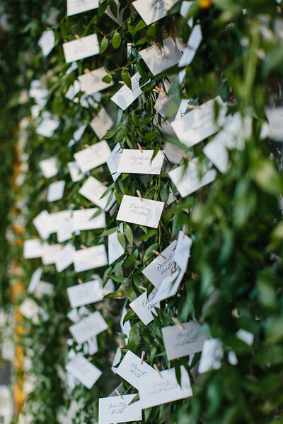 Calligraphy escort cards on hanging greenery for wedding at Castle Hill Inn in Rhode Island