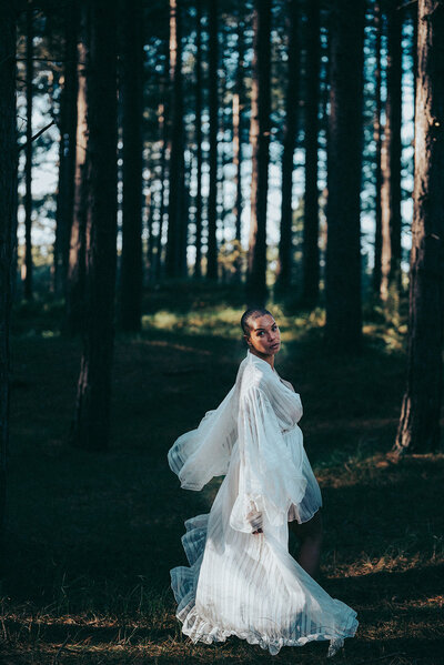 Personal brand image of woman running in the woods wearing whimsical white dress