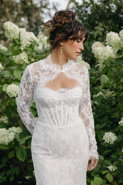 Bride stands in front of a white hydrangea bush 